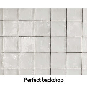 Pode incluir: Um fundo de azulejos brancos com um acabamento texturizado sutil. Os azulejos são dispostos em uma grade, criando uma estética limpa e moderna.