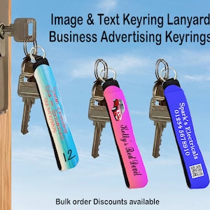 May include: Three colourful keyrings with different designs and text. The keyrings are made of a soft, stretchy material and feature a loop for attaching keys. The text on the keyrings includes business names, phone numbers, and a QR code. The keyrings are hanging on a door handle.