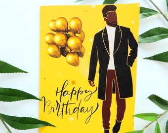 May include: A yellow birthday card with a black silhouette of a person in a long coat, holding a bunch of gold balloons. The words "Happy Birthday" are written in cursive. The card has a white background with green leaves.