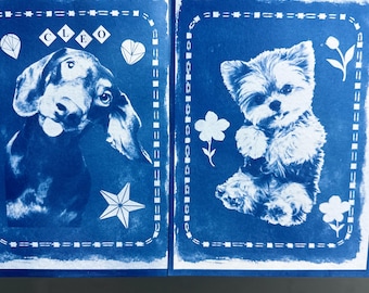 May include: Two blue and white cyanotype prints on paper. The left print features a dachshund with the name CLEO and geometric shapes. The right print shows a small fluffy dog surrounded by flower illustrations. Both have a dashed border.