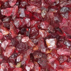 Könnte beinhalten: Nahaufnahme eines Haufens roher roter Rubin-Edelsteine. Die Rohsteine haben verschiedene Formen und Größen, wobei einige Stücke durchscheinender sind als andere.