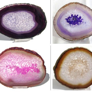 Könnte beinhalten: Vier Agatscheiben mit unterschiedlichen Farbmustern. Die Scheiben sind lila, rosa, weiß und braun. Jede Scheibe hat eine weiße Mitte mit einer kristallinen Textur. Die Scheiben werden auf klaren Acrylständern präsentiert.
