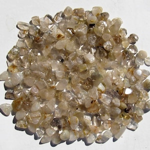 Könnte beinhalten: Ein großer Haufen kleiner, klarer Quarzkristalle mit goldenem Schimmer. Die Kristalle sind getrommelt und haben eine glatte, abgerundete Form.
