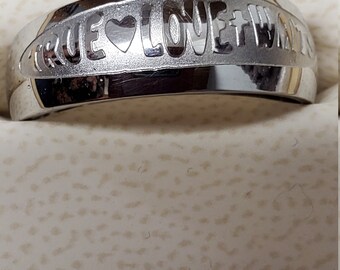 May include: A silver ring with the words "True Love Waits" engraved on it. The words are separated by a heart symbol.
