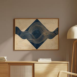 May include: A rectangular wall art piece in a wooden frame featuring a central dark blue diamond shape against a beige textured background. The design includes flowing, thin gold lines that create wave-like patterns across the blue diamond.