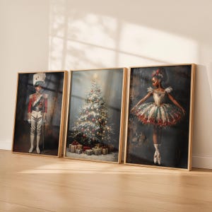 May include: Three framed wall art prints featuring a nutcracker soldier in a red uniform, a decorated Christmas tree with presents, and a ballerina in a festive tutu. Each print is encased in a light wood frame, displaying holiday themes.