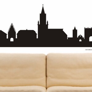 Könnte beinhalten: Schwarz-weiße Silhouette der Skyline der Stadt Neuberg an der Donau, Deutschland. Die Skyline zeigt mehrere Gebäude, darunter eine Kirche mit einem hohen Turm.