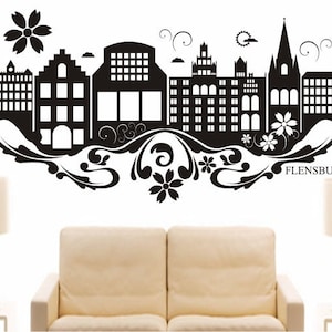 Puede incluir: Silueta en blanco y negro de una ciudad con un diseño floral y la palabra "FLENSBURG" en la parte inferior.