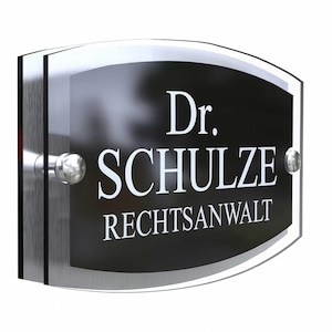 May include: A rectangular black and silver sign with the text "Dr. SCHULZE RECHTSANWALT" in white. The sign has a curved top and is mounted with silver hardware.