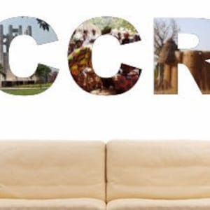 Puede incluir: La palabra "ACCRA" está escrita en letras grandes, cada letra está compuesta por un collage de imágenes de Accra, Ghana. Las letras están en una pared blanca, con un sofá y dos lámparas en primer plano.