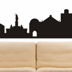 May include: Black and white silhouette of the Nicosia skyline, featuring a church, a statue, and several buildings. The text "NIKOSIA" is visible at the bottom of the image.