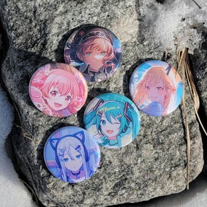 以下が含まれることがあります： 異なるキャラクターの5つの丸いアニメキャラクターボタン。ボタンはカラフルで、さまざまなアニメキャラクターがさまざまな髪型と表情で描かれています。