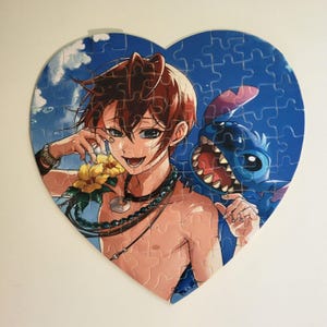 Könnte beinhalten: Ein herzförmiges Puzzle mit einem Comic-Charakter mit blauem Fell und großen Zähnen, der neben einem jungen Mann mit braunen Haaren und einer Halskette steht. Der Hintergrund ist ein blauer Himmel mit weißen Wolken.