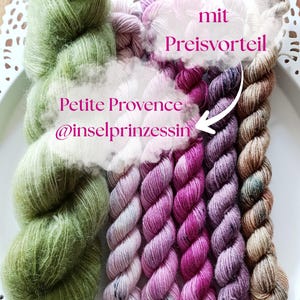 Könnte beinhalten: Ein Set aus sechs Garnsträngen in verschiedenen Texturen und Farben, darunter ein großer, flauschiger olivgrüner Strang und fünf kleinere, gedrehte Stränge in Hellrosa, Magenta, Dunkellila und Braun, mit dem Text Garnset mit Preisvorteil, Petite Provence und @inselprinzessin.