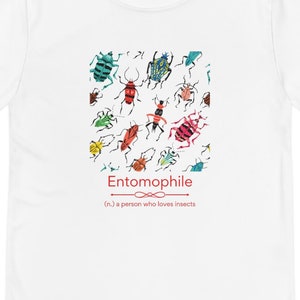 May include: White long-sleeve shirt featuring a colorful insect graphic. The graphic includes various insects in red, green, blue, and orange. The word "Entomophile" is printed below the graphic, along with a definition.