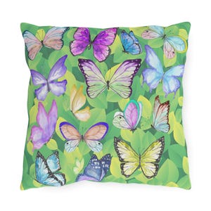 May include: Square throw pillow featuring a pattern of colorful butterflies in shades of purple, blue, yellow, and pink. The butterflies are set against a background of green leaves. The pillow is a decorative item.