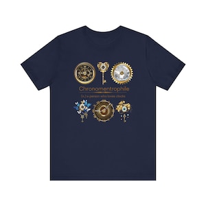May include: Navy blue t-shirt with a gold and silver design of clock faces and keys. The text "Chronometrophille (n.) a person who loves clocks" is printed on the shirt.