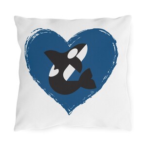 May include: White square pillow featuring a blue heart with a distressed texture. Inside the heart is a black and white orca whale illustration. The pillow is a decorative item.