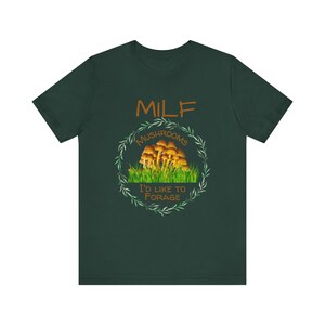 May include: A dark green t-shirt with a white circle containing the text "MILF Mushrooms I'd like to forage" and a graphic of mushrooms in a forest.