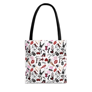 Puede incluir: Bolso tote blanco con asa negra. El bolso presenta un patrón repetido de ilustraciones fetichistas rojas, negras y blancas, incluyendo labios, máscaras de conejito, látigos y otras imágenes relacionadas.