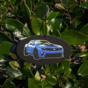 Puede incluir: Un ambientador de coche azul con fondo negro. El coche es un Chevrolet Camaro.