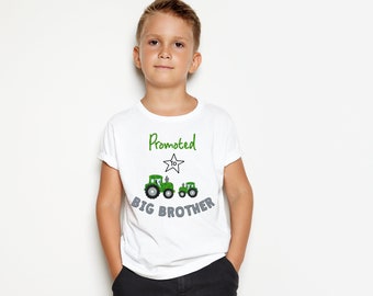 May include: White t-shirt with green text that says "Promoted to Big Brother" with a star and two green toy tractors.