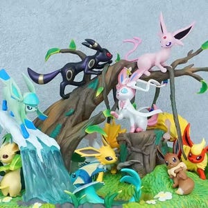 Puede incluir: Un conjunto de figuras con varias criaturas coloridas posadas sobre una estructura de árbol marrón. La escena incluye una cascada de hielo azul claro, follaje verde y pequeñas flores blancas, con personajes en tonos negro, rosa, amarillo y marrón.