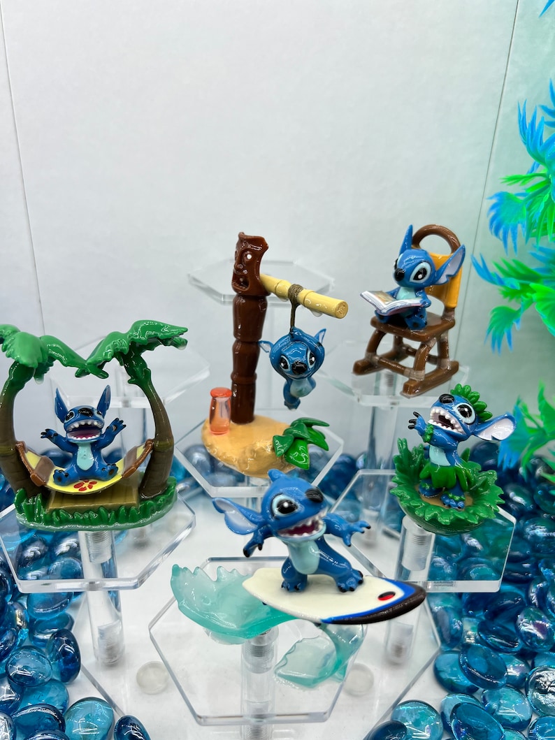 Pu&ograve; includere: Sei figurine blu di Stitch del film Disney Lilo & Stitch. Ogni figurina &egrave; in posa in un'azione diversa, tra cui il surf, il relax in un'amaca e la lettura di un libro. Le figurine sono esposte su un supporto esagonale con pietre di vetro blu.