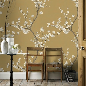 Elegante carta da parati ispirata alla chinoiserie con rami in fiore su sfondo color oro senape, murale staccabile e attaccabile