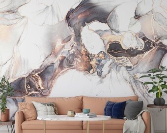 Puede incluir: Un interior de sala de estar con un sofá rosa empolvado, una mesa de café de mármol blanco y una alfombra geométrica en blanco y negro. La pared detrás del sofá presenta una gran pintura abstracta en tonos grises, blancos y dorados.