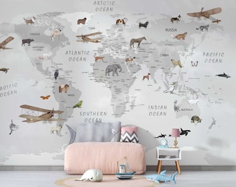 Puede incluir: Un mapa del mundo gris con ilustraciones de animales y etiquetas de texto escritas a mano para los continentes y los océanos. El mapa está en una pared blanca con un sofá rosa y una mesita auxiliar pequeña con una lámpara.