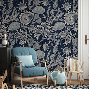 May include: Dark blue wallpaper featuring a repeating pattern of seashells and coral in a cream color. The wallpaper is the backdrop for a blue armchair, a small wooden side table, and a black and white patterned rug.