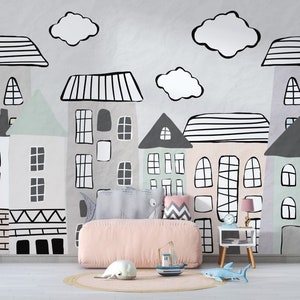 May include: A pink upholstered bed with a white and gray patterned headboard, placed in front of a wall with a black and white illustration of a city skyline. The illustration features houses with windows and doors, and clouds.