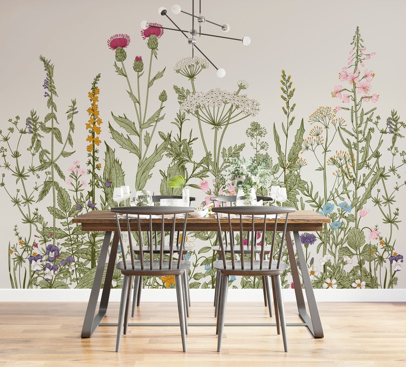 May include: A dining room with a floral wallpaper featuring a variety of flowers and plants in shades of pink, yellow, green, and blue. A wooden table with two black chairs is in the foreground.