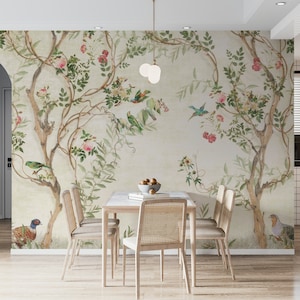 May include: A dining room scene featuring a floral wallpaper with birds and trees. A light wood table with a marble top is surrounded by four chairs with woven backs. A bowl of fruit sits on the table, and a pendant light hangs above.