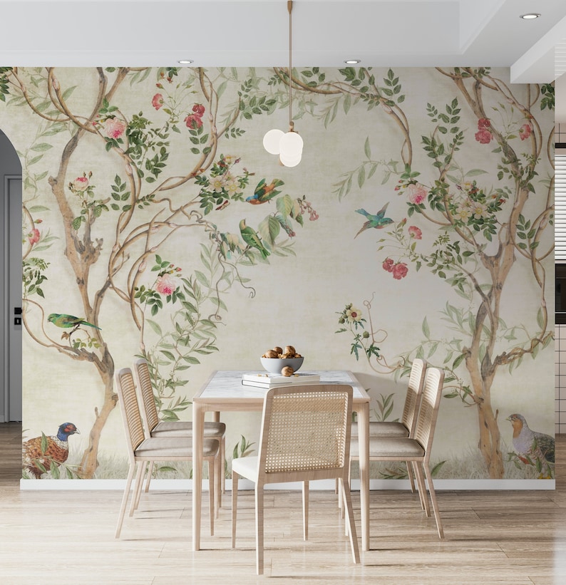 May include: A dining room scene featuring a floral wallpaper with birds and trees. A light wood table with a marble top is surrounded by four chairs with woven backs. A bowl of fruit sits on the table, and a pendant light hangs above.