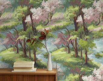 May include: A stack of white books and a tall, slender white vase containing a single branch with dark brown leaves sit on a wooden surface against a wallpaper featuring a repeating painted landscape of green trees and pink blossoms.