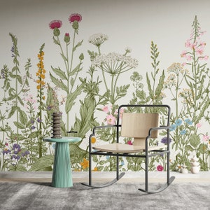 May include: A rocking chair with a wooden seat and black metal frame sits in front of a wall with a floral wallpaper design. The wallpaper features a variety of flowers and plants in shades of green, pink, blue, and yellow.