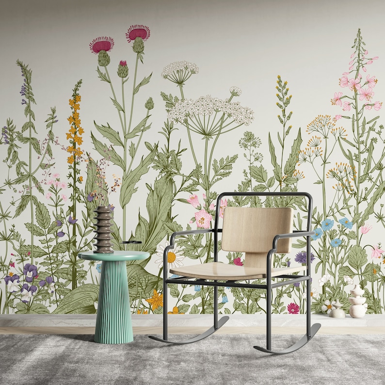 May include: A rocking chair with a wooden seat and black metal frame sits in front of a wall with a floral wallpaper design. The wallpaper features a variety of flowers and plants in shades of green, pink, blue, and yellow.