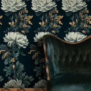 May include: Dark teal floral wallpaper featuring large white and gold flowers with dark green leaves. A dark green velvet sofa with wooden trim is in the foreground, set against a wooden floor.