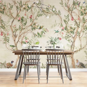 May include: A dining room scene featuring a wooden table and chairs set against a floral wallpaper backdrop. The wallpaper showcases a botanical design with trees, birds, and flowers in shades of green, pink, and beige. The table is set with glassware.