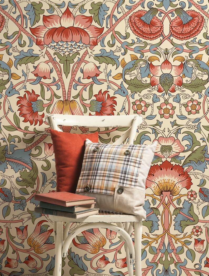 Puede incluir: Una silla de mimbre blanca con dos almohadas, una roja y otra a cuadros, y tres libros apilados en el asiento. La silla est&aacute; delante de una pared cubierta con un papel tapiz floral con un patr&oacute;n repetitivo de flores rojas, rosas, amarillas y azules.