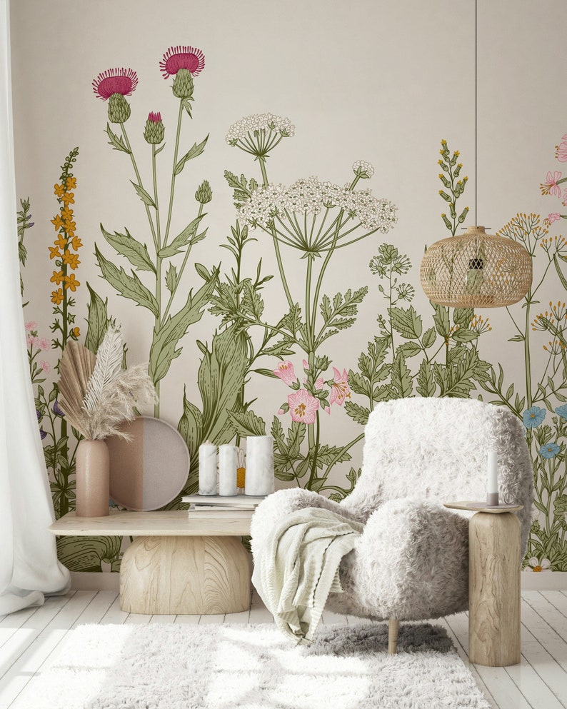 May include: A living room interior design featuring a white fluffy armchair with a throw blanket, a wooden coffee table, and a beige wall with a floral wallpaper design. The wallpaper features a variety of flowers and plants in shades of pink, green, and yellow.