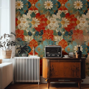 Könnte beinhalten: Ein Raum mit einer lebendigen floralen Tapete in Rot, Türkis und Weiß. Ein Vintage-Holzschrank beherbergt ein schwarzes Radio und dekorative Gegenstände. Ein weißer Heizkörper und Topfpflanzen sind ebenfalls sichtbar, vor einem Holzboden.