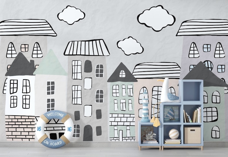 May include: A light blue bookshelf with six shelves, filled with books and decorative items. The bookshelf is in front of a wall with a whimsical mural of houses and clouds, featuring a life preserver with the text "Welcome on Board".