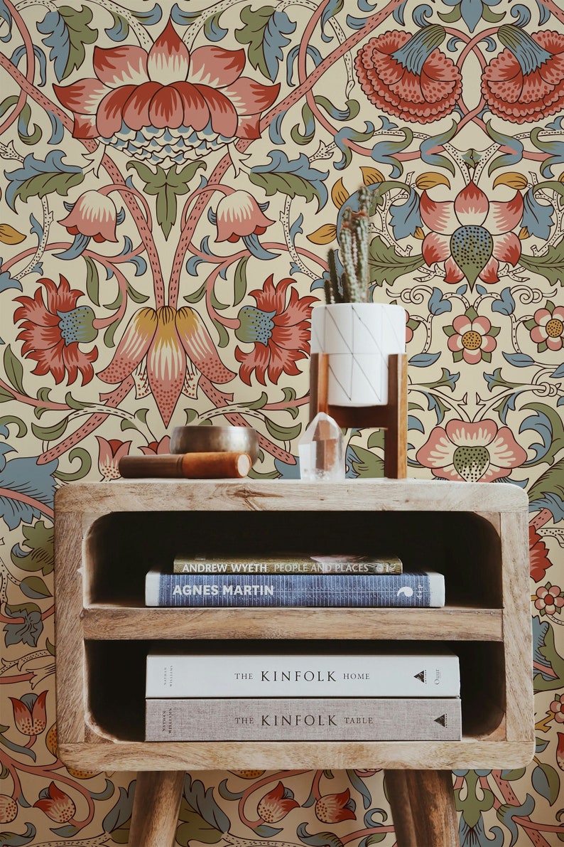 Puede incluir: Una mesa auxiliar de madera con dos estantes, con un fondo de papel tapiz floral. El estante superior tiene un taz&oacute;n peque&ntilde;o y un cristal, mientras que el estante inferior contiene tres libros: "Andrew Wyeth: People and Places", "Agnes Martin" y "The Kinfolk Home".