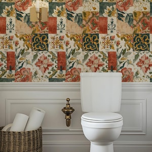 May include: A bathroom interior with a white toilet, a wicker basket holding toilet rolls, and floral wallpaper. The wallpaper displays a repeating pattern of red, green, and yellow floral squares. A gold wall-mounted light fixture is also visible.