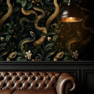 Könnte beinhalten: Ein braunes, gestepptes Ledersofa vor einer Wand mit einer Tapete, die ein wiederkehrendes Muster aus goldenen Schlangen, dunkelgrünen Blättern und weißen Blüten zeigt, beleuchtet von einer schwarzen, kuppelförmigen Pendelleuchte.