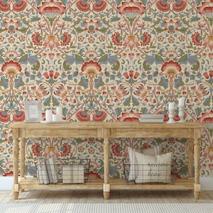 Puede incluir: Una consola de madera con un fondo de papel tapiz estampado. El papel tapiz presenta un dise&ntilde;o floral repetitivo en tonos rojos, azules y verdes. La mesa tiene dos estantes y est&aacute; decorada con velas, libros y cestas.