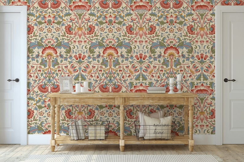 Puede incluir: Una consola de madera con un fondo de papel tapiz estampado. El papel tapiz presenta un dise&ntilde;o floral repetitivo en tonos rojos, azules y verdes. La mesa tiene dos estantes y est&aacute; decorada con velas, libros y cestas.